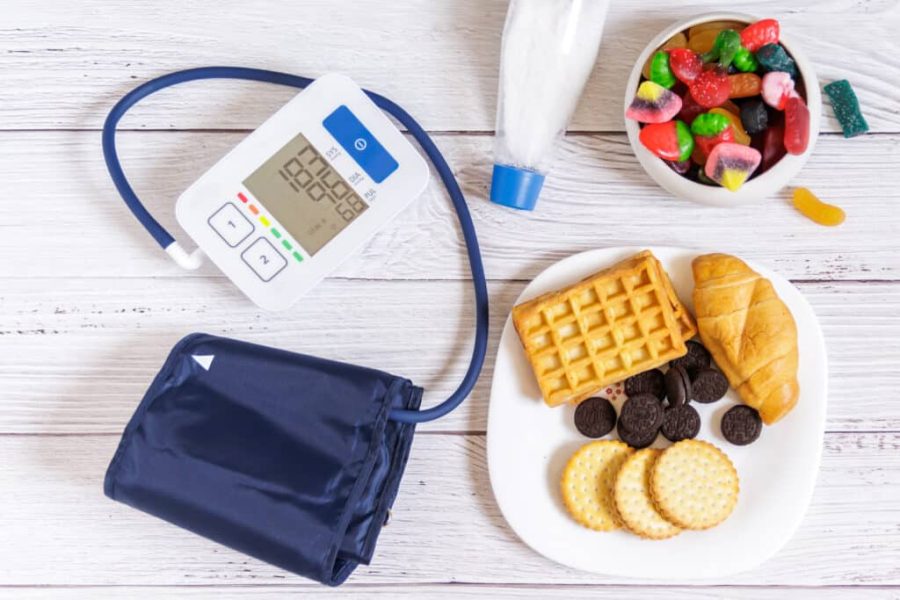 Blood pressure monitor on a wooden table with salt and sweets. Arterial hypertension. Background.